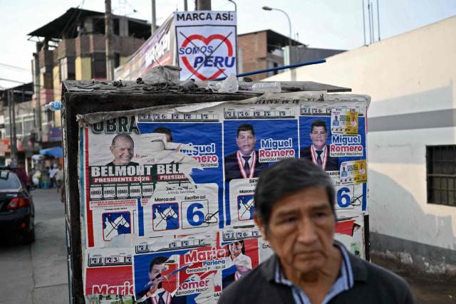 A man waits for a bus next to political propaganda in the Villa Maria del Triunfo neighborhood in Lima, on April 8, 2026. Peruvians will choose from a bewildering array of 35 presidential candidates on April 12, 2026, electing the next leader of an Andean nation beset by crime and a string of short-lived, scandal tainted presidencies. (Photo by Luis ROBAYO / AFP)