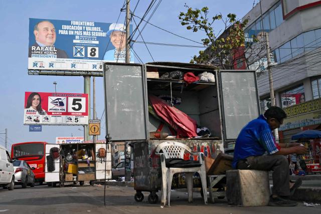 A man sits near political propaganda of presidential candidate Rafael Lopez Aliaga for the  Popular Renewal, in Lima, on April 8, 2026. Peruvians will choose from a bewildering array of 35 presidential candidates on April 12, 2026, electing the next leader of an Andean nation beset by crime and a string of short-lived, scandal tainted presidencies. (Photo by Luis ROBAYO / AFP)