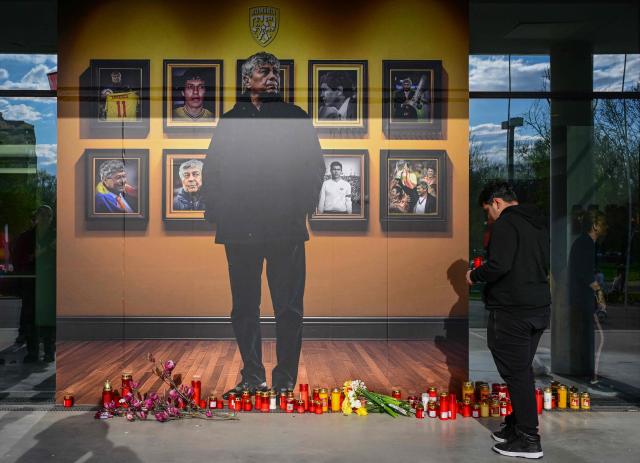 People light candles next to a portrait of Romanian football legend Mircea Lucescu at the National Arena in Bucharest, Romania, April 8, 2026. Fans and figures from the sporting world gathered at the country's largest stadium to pay their final respects to the former national team coach and one of the most decorated managers in history, who passed away on April 7, 2026, at the age of 80. (Photo by Daniel MIHAILESCU / AFP)
