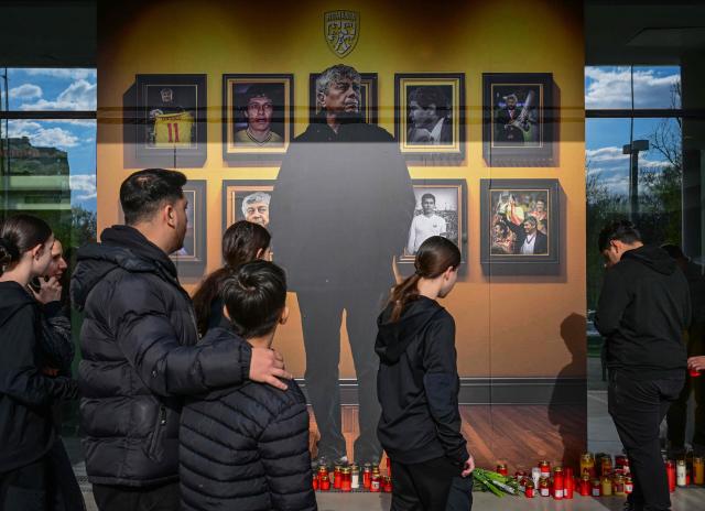 People light candles next to a portrait of Romanian football legend Mircea Lucescu at the National Arena in Bucharest, Romania, April 8, 2026. Fans and figures from the sporting world gathered at the country's largest stadium to pay their final respects to the former national team coach and one of the most decorated managers in history, who passed away on April 7, 2026, at the age of 80. (Photo by Daniel MIHAILESCU / AFP)