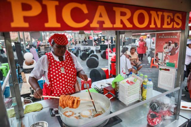 A street vendor prepares 'picarones', a traditional Peruvian dessert of crispy fried rings made from sweet potato and squash dough, at the Alameda Chabuca Granda, in Lima, on April 7, 2026.. (Photo by Connie FRANCE / AFP)