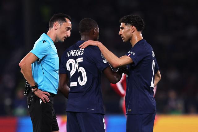 Paris Saint-Germain's Portuguese defender #25 Nuno Mendes (C) reacts with Paris Saint-Germain's Moroccan defender #02 Achraf Hakimi (R) next to Spanish referee Jose Maria Sanchez (L) during  the UEFA Champions League quarter-final first leg football match between Paris Saint-Germain (PSG) and Liverpool FC at the Parc des Princes stadium in Paris on April 8, 2026. (Photo by FRANCK FIFE / AFP)