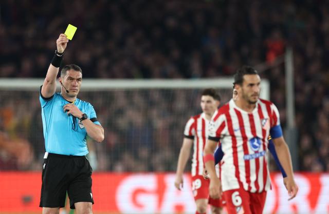 Atletico Madrid's Spanish midfielder #06 Koke (R) receives a yellow card from Romanian referee Istvan Kovacs during the UEFA Champions League quarter final first leg football match between FC Barcelona and Club Atletico de Madrid at Camp Nou Stadium in Barcelona on April 8, 2026. (Photo by Josep LAGO / AFP)