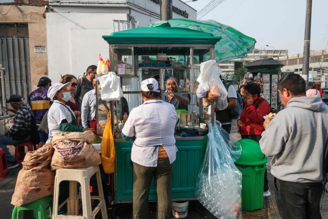 Passers-by wait for their breakfast at a street stall in Jiron Quilca, in Lima on April 8, 2026. (Photo by Connie FRANCE / AFP)