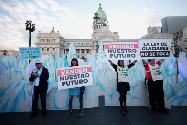 Demonstrators show signs that read in Spanish, "They're selling our future," in front of the Congress building during a protest against the modifications in glacier law in Buenos Aires on April 8, 2026. Argentine deputies will debate on April 8, 2026 a government proposal calling on the provinces to redefine glacier protection zones in order to expand mining operations. (Photo by TOMAS CUESTA / AFP)