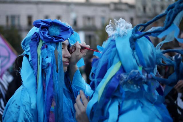 Demonstrators wearing costumes apply makeup during a protest against the modifications in glacier law in Buenos Aires on April 8, 2026. Argentine deputies will debate on April 8, 2026 a government proposal calling on the provinces to redefine glacier protection zones in order to expand mining operations. (Photo by TOMAS CUESTA / AFP)