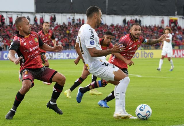 Santos' forward #21 Moises (C) fights for the ball with Deportivo Cuenca's midfielder #08 Edison Vega (L) and Argentine forward #07 Lucas Mancinelli during the Copa Sudamericana group stage football match between Ecuador's Deportivo Cuenca and Brazil's Santos at the Alejandro Serrano Aguilar stadium in Cuenca, Ecuador, on April 8, 2026. (Photo by Fernando MACHADO / AFP)