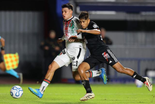 Palestino's defender #29 Ian Garguez and Deportivo Riestra's defender #13 Rodrigo Gallo fight for the ball during the Copa Sudamericana group stage football match between Argentina's Deportivo Riestra and Chile's Palestino at the Pedro Bidegain stadium in Buenos Aires on April 8, 2026. (Photo by ALEJANDRO PAGNI / AFP)