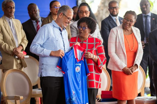 Haitian Prime Minister Alix Didier Fils-Aime (L) receives a team jersey from the Haitian Football Federation (FHF) President Marie Monique Andre during a presentation to the Haitian Football Federation of World Cup qualification bonuses and team preparations at the Villa d’Accueil in Port-au-Prince, on April 8, 2026. (Photo by Clarens SIFFROY / AFP)
