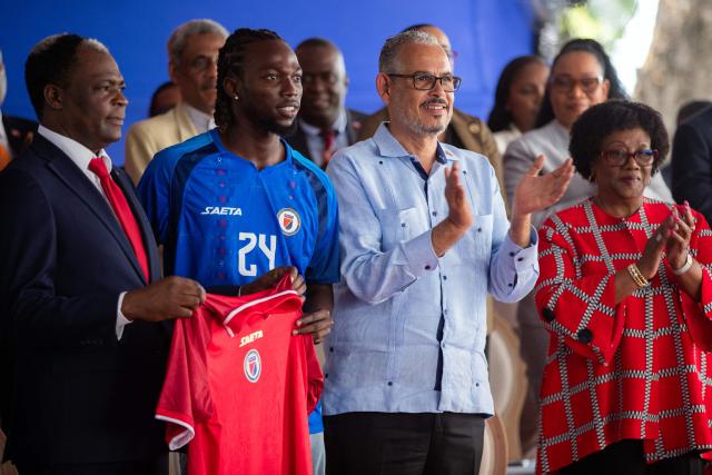 Haitian Prime Minister Alix Didier Fils-Aime (2nd-R), Haitian Football Federation (FHF) President Marie Monique Andre (R), Sports Minister Pythagore Dumas (L) and player Woodensky Pierre pose for a photo during a presentation to the Haitian Football Federation of World Cup qualification bonuses and team preparations at the Villa d’Accueil in Port-au-Prince, on April 8, 2026. (Photo by Clarens SIFFROY / AFP)