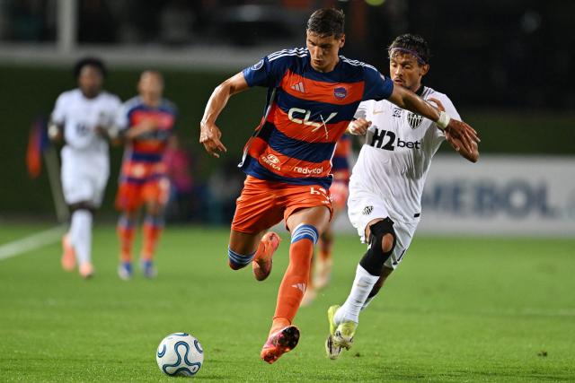 Puerto Cabello's Serbian defender #63 Stefan Obradovic and Atletico Mineiro's midfielder #10 Gustavo Scarpa fight for the ball during the Copa Sudamericana group stage football match between Venezuela's Academia Puerto Cabello and Brazil's Atletico Mineiro at the Misael Delgado stadium in Valencia, state of Carabobo, Venezuela, on April 8, 2026. (Photo by Juan BARRETO / AFP)
