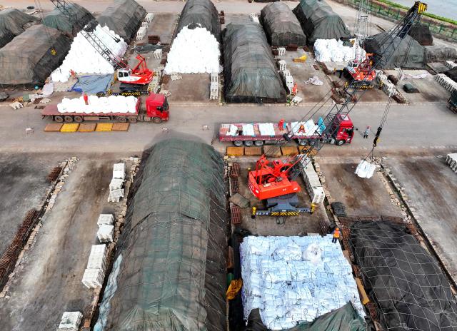 An aerial photo shows workers handling imported fertilisers at the Lianyungang port, in eastern China's Jiangsu province on April 8, 2026. (Photo by CN-STR / AFP) / China OUT