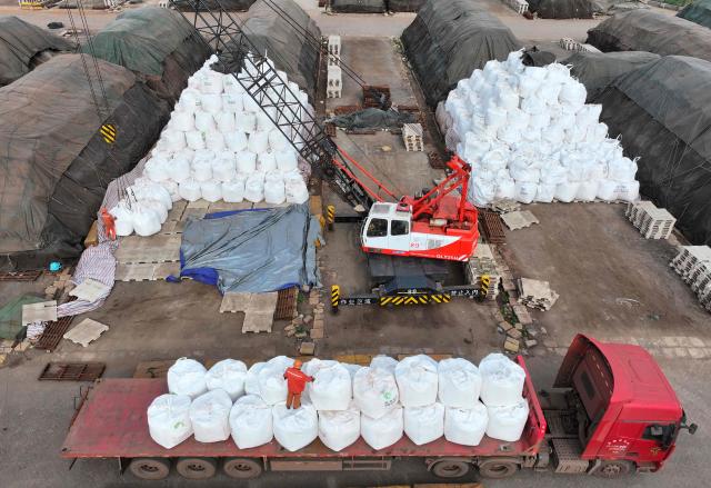An aerial photo shows workers handling imported fertilisers at the Lianyungang port, in eastern China's Jiangsu province on April 8, 2026. (Photo by CN-STR / AFP) / China OUT