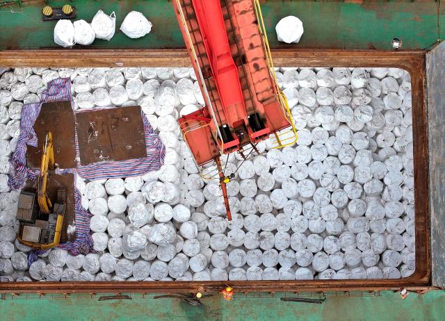 An aerial photo shows workers unloading imported fertilisers at the Lianyungang port, in eastern China's Jiangsu province on April 8, 2026. (Photo by CN-STR / AFP) / China OUT