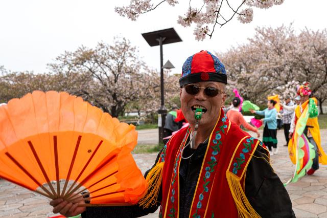A man performs in a traditional ethnic folk dance from Northeast China at Ojima Komatsugawa Park to mark the cherry blossoms in full bloom in Tokyo on April 9, 2026. (Photo by Philip FONG / AFP)