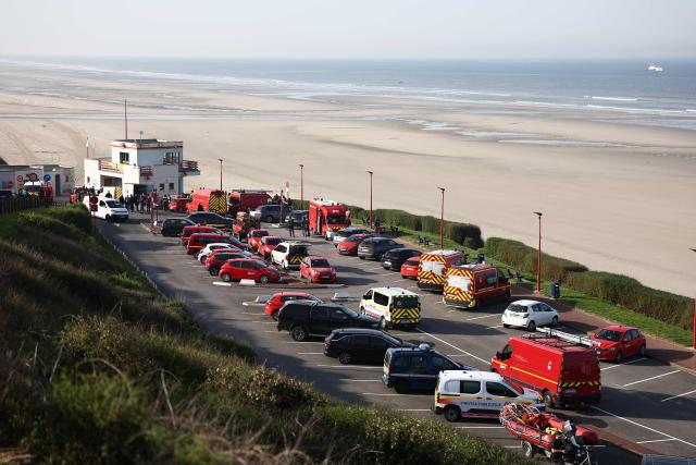 Rescue vehicles are parked on a parking lot overseeing the beach as medical units gather after an attempt to cross the English Channel illegally turned tragic with several migrants found in cardiac arrest, in France's Pas-de-Calais northern coastal city of Equihen-Plage on April 9, 2026. (Photo by Sameer AL-DOUMY / AFP)