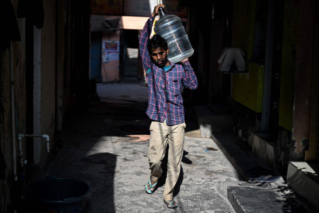 A migrant worker carries a plastic water container in New Delhi on April 9, 2026. (Photo by Sajjad HUSSAIN / AFP)