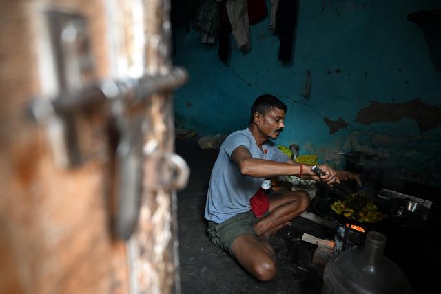A migrant worker cooks food on a wood-fired stove inside his rented room in New Delhi on April 9, 2026. (Photo by Sajjad HUSSAIN / AFP)