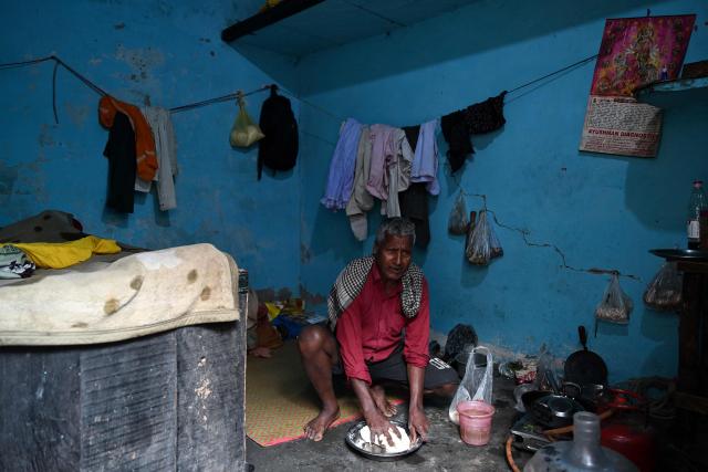 A migrant worker prepares food inside his rented room in New Delhi on April 9, 2026. (Photo by Sajjad HUSSAIN / AFP)