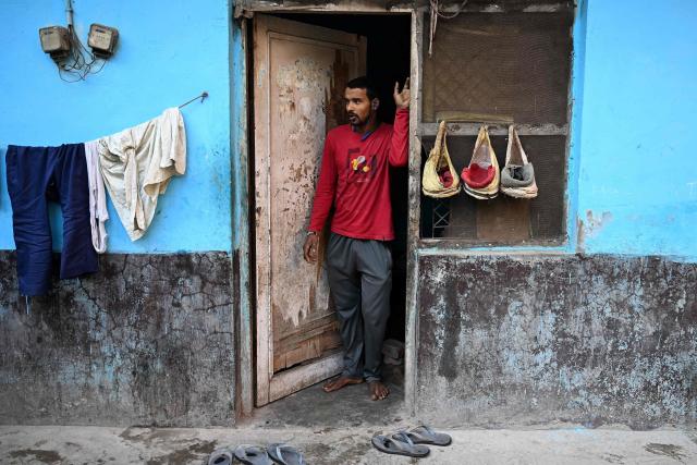 A migrant worker stands at the entrance of his rented room in New Delhi on April 9, 2026. (Photo by Sajjad HUSSAIN / AFP)