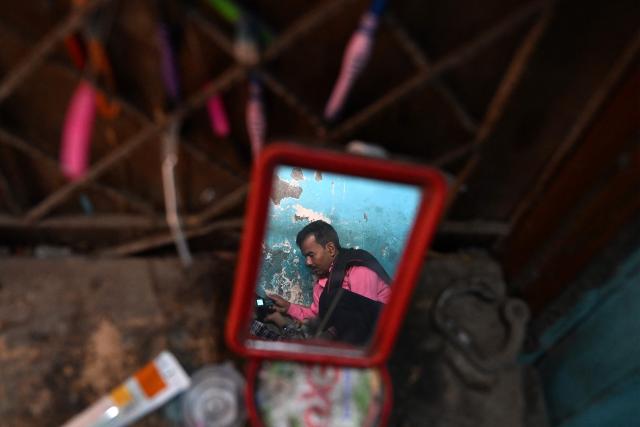 A migrant worker reflected on a mirror inside his rented room in New Delhi on April 9, 2026. (Photo by Sajjad HUSSAIN / AFP)