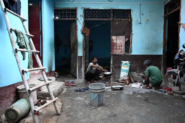A migrant worker cooks food on a wood-fired stove outside his rented room in New Delhi on April 9, 2026. (Photo by Sajjad HUSSAIN / AFP)