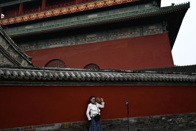 A woman poses for a picture next to the Drum Tower in Beijing on April 9, 2026. (Photo by Pedro PARDO / AFP)