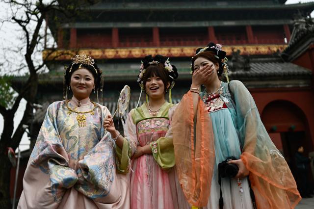 Women wearing traditional Chinese costumes are seen in a tourist area in Beijing on April 9, 2026. (Photo by Pedro PARDO / AFP)