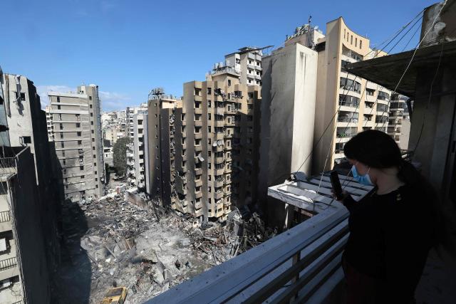 A woman takes a picture with her mobile phone of Lebanese first responders searching under the rubble at the site of an Israeli airstrike that targeted a building the day before in Beirut's Corniche al-Mazraa neighbourhood on April 9, 2026. Rescuers searched for survivors under the rubble of destroyed buildings in Beirut as Lebanon observed a day of mourning after Israeli strikes across the country killed more than 200. (Photo by Ibrahim AMRO / AFP)