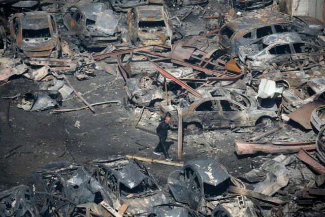 A Lebanese man walks amid charred cars at the site of an Israeli airstrike that targeted a building the day before in Beirut's Corniche al-Mazraa neighbourhood on April 9, 2026. Rescuers searched for survivors under the rubble of destroyed buildings in Beirut as Lebanon observed a day of mourning after Israeli strikes across the country killed more than 200. (Photo by Ibrahim AMRO / AFP)