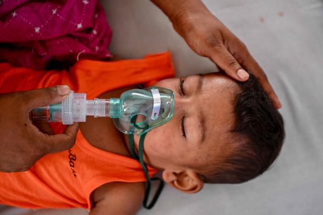 A mother holds a nebulizer on the face of her child receiving treatment for measles in a paediatric ward at a hospital in Dhaka on April 9, 2026. Bangladesh said it suspected measles killed at least 98 children in the past three weeks, official data showed on April 5, with Dhaka ramping up vaccination efforts in the worst-affected areas. (Photo by Munir UZ ZAMAN / AFP)