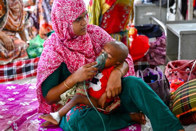 A mother holds a nebulizer on the face of her child receiving treatment for measles in a paediatric ward at a hospital in Dhaka on April 9, 2026. Bangladesh said it suspected measles killed at least 98 children in the past three weeks, official data showed on April 5, with Dhaka ramping up vaccination efforts in the worst-affected areas. (Photo by Munir UZ ZAMAN / AFP)