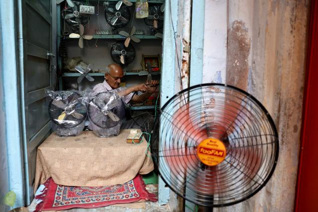 A man repairs a table fan at his shop in Varanasi on April 9, 2026. (Photo by Niharika KULKARNI / AFP)