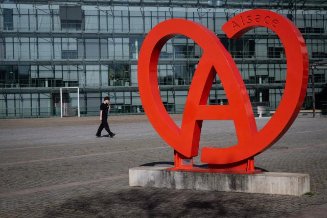 A man passes by the logo of the Collectivite Europeene d'Alsace (CEA), on April 9, 2026, in Colmar, eastern France. France's parliament lower house, the National Assembly, passed on April 8, 2026 a revised version of the bill aimed at removing Alsace from the Grand Est region at its first reading, although the future of the bill remains uncertain at this stage. (Photo by SEBASTIEN BOZON / AFP)