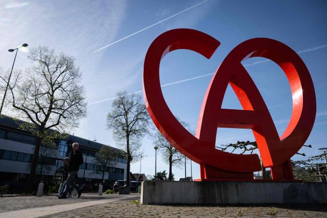 People pass by the logo of the Collectivite Europeene d'Alsace (CEA), on April 9, 2026, in Colmar, eastern France. France's parliament lower house, the National Assembly, passed on April 8, 2026 a revised version of the bill aimed at removing Alsace from the Grand Est region at its first reading, although the future of the bill remains uncertain at this stage. (Photo by SEBASTIEN BOZON / AFP)