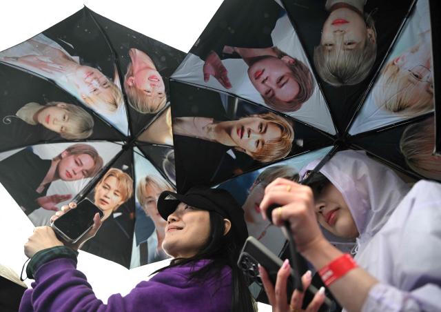 BTS fans hold umbrellas featuring members of K-pop boy band BTS as they arrive at a stadium where the group will perform in Goyang on April 9, 2026. South Korean K-pop megastars BTS kicked off their world tour on April 9, riding the momentum of a chart-topping comeback album and a landmark performance in the heart of Seoul. (Photo by Jung Yeon-je / AFP)