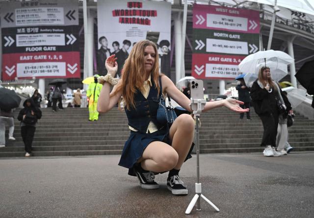 A BTS fan dances outside a stadium where K-pop boy band BTS will perform in Goyang on April 9, 2026. South Korean K-pop megastars BTS kicked off their world tour on April 9, riding the momentum of a chart-topping comeback album and a landmark performance in the heart of Seoul. (Photo by Jung Yeon-je / AFP)