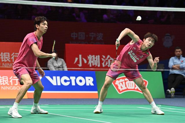 Hu Keyuan (R) and Lin Xiangyi (L) of China hit a return to Aaron Chia and Soh Wooi Yik of Malaysia during their men's doubles match at the Badminton Asia Championship in Ningbo, eastern China's Zhejiang province on April 9, 2026. (Photo by CN-STR / AFP) / China OUT