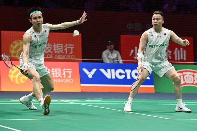 Soh Wooi Yik (L) and Aaron Chia (R) of Malaysia hit a return to Hu Keyuan and Lin Xiangyi of China during their men's doubles match at the Badminton Asia Championship in Ningbo, eastern China's Zhejiang province on April 9, 2026. (Photo by CN-STR / AFP) / China OUT