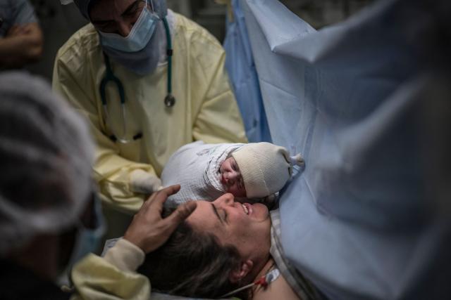 The newborn daughter of Israeli woman Sarah Bird, is presented to the mother at the operating theatre of the neonatal unit in the underground bomb shelter built into the Carmel Medical Center in the northern city of Haifa, on April 9, 2026. The hospital, built in the tip of the one of the mountains of the Carmel Mountain Range is part of the Clalit Health Services, the largest health organisation in Israel running 14 hospitals across the country. At least 14 rocket alerts sounded through April 9 morning in communities near Israel's northern border with Lebanon as Israeli forces fight Hezbollah despite the US-Iran ceasefire. (Photo by MARCO LONGARI / AFP)