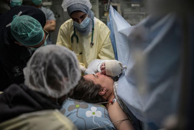 Israeli woman Sarah Bird kisses her newborn daughter at the operating theatre of the neonatal unit in the underground bomb shelter built into the Carmel Medical Center in the northern city of Haifa, on April 9, 2026. The hospital, built in the tip of the one of the mountains of the Carmel Mountain Range is part of the Clalit Health Services, the largest health organisation in Israel running 14 hospitals across the country. At least 14 rocket alerts sounded through April 9 morning in communities near Israel's northern border with Lebanon as Israeli forces fight Hezbollah despite the US-Iran ceasefire. (Photo by MARCO LONGARI / AFP)