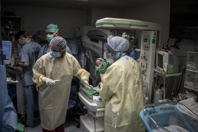 Midwifes (in Yellow) tend to Israeli woman Sarah Bird's third baby at the operating theatre of the neonatal unit in the underground bomb shelter built into the Carmel Medical Center in the northern city of Haifa, on April 9, 2026. The hospital, built in the tip of the one of the mountains of the Carmel Mountain Range is part of the Clalit Health Services, the largest health organisation in Israel running 14 hospitals across the country. At least 14 rocket alerts sounded through April 9 morning in communities near Israel's northern border with Lebanon as Israeli forces fight Hezbollah despite the US-Iran ceasefire. (Photo by MARCO LONGARI / AFP)