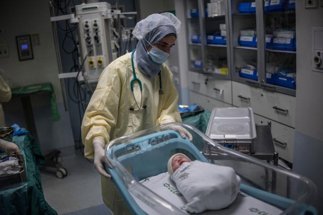 A midwife pushes the cot with the newborn daughter of Israeli woman Sarah Bird, at the operating theatre of the neonatal unit in the underground bomb shelter built into the Carmel Medical Center in the northern city of Haifa, on April 9, 2026. The hospital, built in the tip of the one of the mountains of the Carmel Mountain Range is part of the Clalit Health Services, the largest health organisation in Israel running 14 hospitals across the country. At least 14 rocket alerts sounded through April 9 morning in communities near Israel's northern border with Lebanon as Israeli forces fight Hezbollah despite the US-Iran ceasefire. (Photo by MARCO LONGARI / AFP)