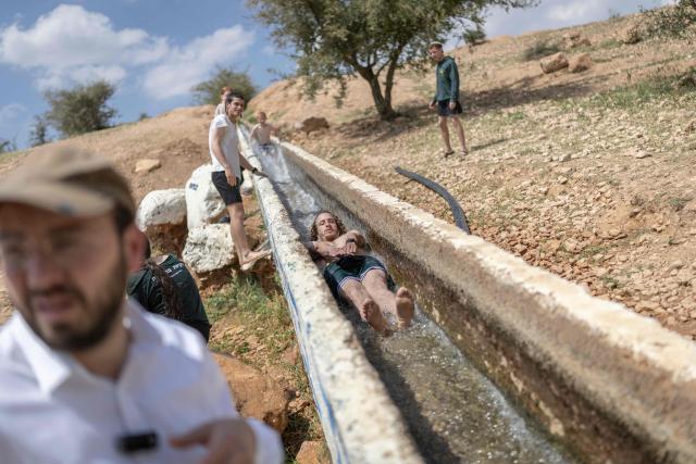 Israeli settlers gather at a water slide in the Israeli-occupied West Bank village of Ras Ein al-Auja on April on April 9, 2026. Israel vowed more strikes against Hezbollah on April 9, dismissing mounting international demands that the fragile truce between the United States and Iran in the Gulf be expanded to cover the war in Lebanon. (Photo by Ilia YEFIMOVICH / AFP)