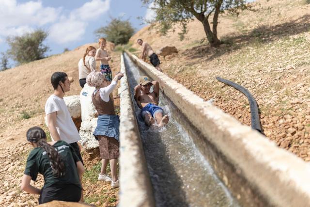 Israeli settlers gather at a water slide in the Israeli-occupied West Bank village of Ras Ein al-Auja on April on April 9, 2026. Israel vowed more strikes against Hezbollah on April 9, dismissing mounting international demands that the fragile truce between the United States and Iran in the Gulf be expanded to cover the war in Lebanon. (Photo by Ilia YEFIMOVICH / AFP)