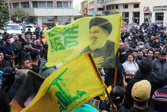 Hezbollah supporters wave a flag bearing a portrait of slain Hezbollah leader Hassan Nasrallah as they stage an anti-government protest outside the Lebanese governmental palace in Beirut on April 9, 2026. Lebanon's cabinet on April 9 instructed security forces to restrict weapons in Beirut exclusively to state institutions, in a warning to Hezbollah a day after Israel launched strikes across the country including the capital. (Photo by Ibrahim AMRO / AFP)