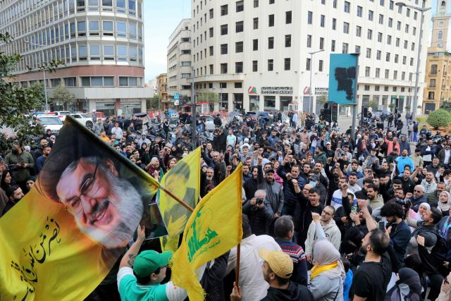 Hezbollah supporters wave a flag bearing a portrait of slain Hezbollah leader Hassan Nasrallah as they stage an anti-government protest outside the Lebanese governmental palace in Beirut on April 9, 2026. Lebanon's cabinet on April 9 instructed security forces to restrict weapons in Beirut exclusively to state institutions, in a warning to Hezbollah a day after Israel launched strikes across the country including the capital. (Photo by Ibrahim AMRO / AFP)