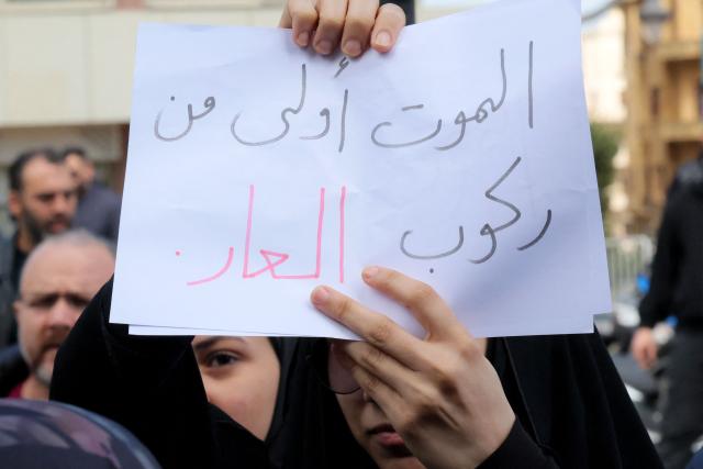 A Hezbollah supporter holds a placard that reads in Arabic: "Death is more honourable than disgrace", during an anti-government protest outside the Lebanese governmental palace in Beirut on April 9, 2026. Lebanon's cabinet on April 9 instructed security forces to restrict weapons in Beirut exclusively to state institutions, in a warning to Hezbollah a day after Israel launched strikes across the country including the capital. (Photo by ibrahim AMRO / AFP)