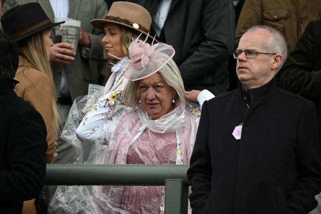 A woman covers herself with a plastic poncho on the opening day of the Grand National Festival horse race meeting at Aintree Racecourse in Liverpool, north-west England, on April 9, 2026. (Photo by Paul ELLIS / AFP)