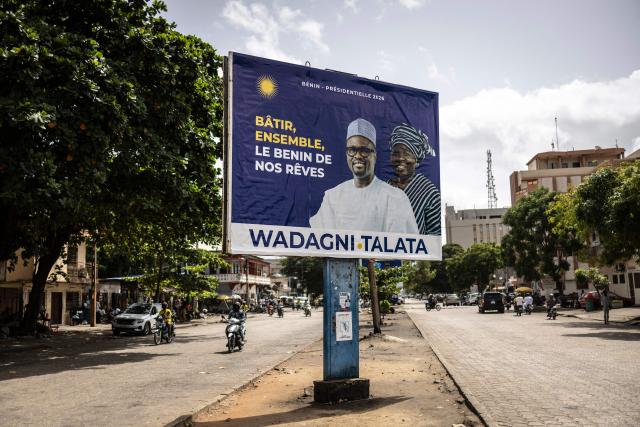 Commuters ride past an election billboard of Romuald Wadagni, presidential candidate, and Mariam Chabi Talata, vice presidential candidate in Cotonou on April 9, 2026, ahead of Benin's presidential election scheduled for April 12, 2026. (Photo by OLYMPIA DE MAISMONT / AFP)